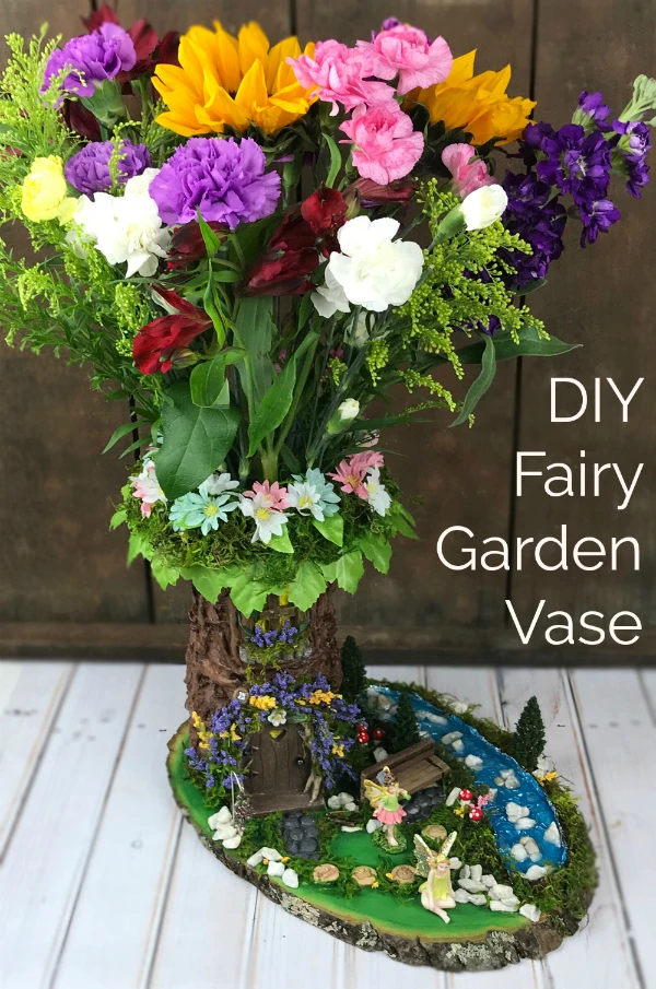 GORGEOUS!  Learn how to make a DIY fairy garden vase with a plain florist's vase!  This project tutorial shows you how to create this stunning fairy garden scene.  It's easier than you might think!